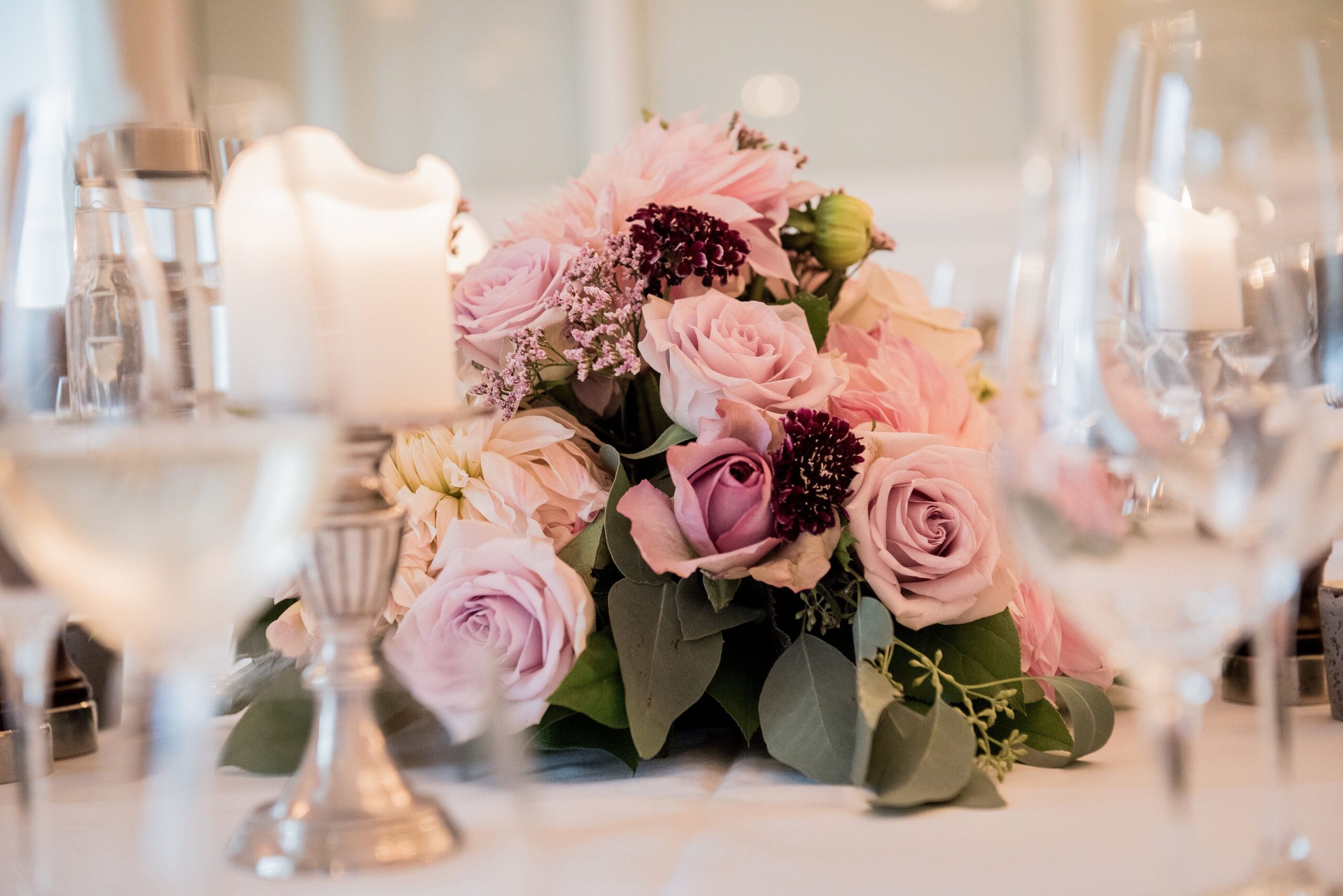 Beautiful pink rose centerpiece with candles on an elegant dining table setting.