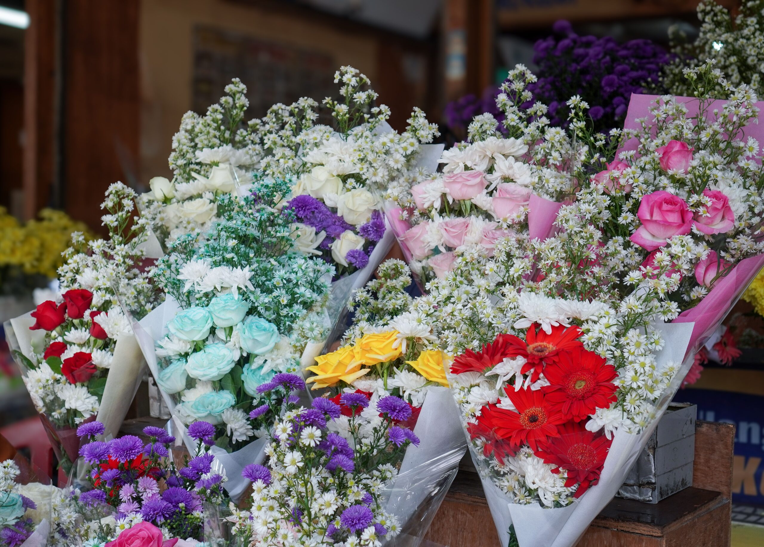 Colorful flower bouquets displayed in a floral shop with roses and daisies.