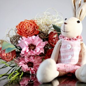 Home Adorable stuffed rabbit toy with a vibrant floral bouquet, perfect for decoration.